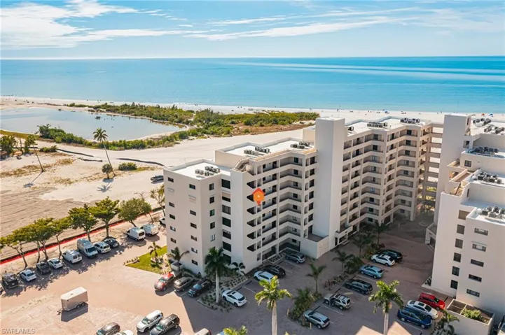 Drone / aerial view of apartment complex and waterfront with a beach