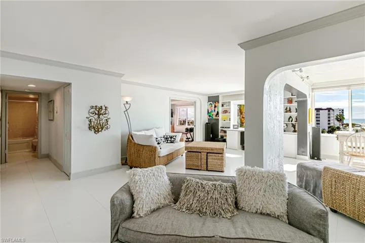 Living area featuring arched walkways, crown molding, healthy amount of natural light, and built in features