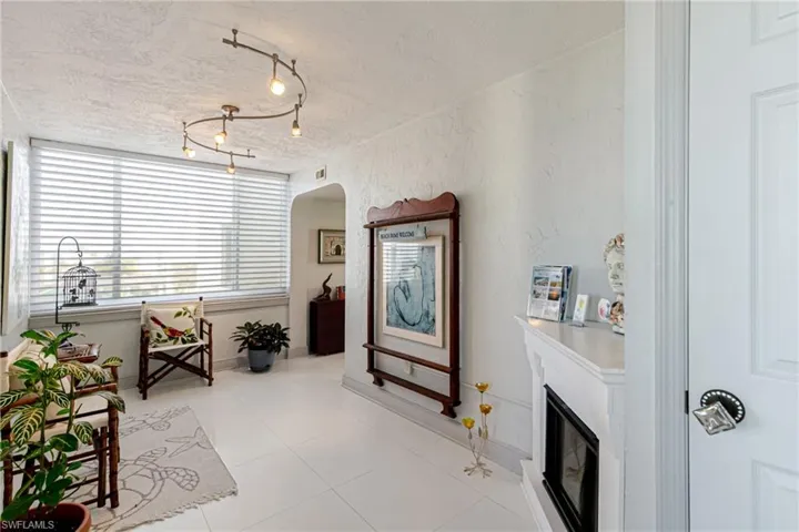 Living area with a glass covered fireplace, arched walkways, a textured wall, a textured ceiling, and light tile patterned floors