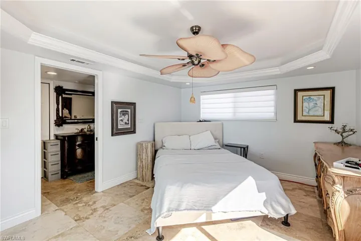 Bedroom with ornamental molding, a ceiling fan, and a tray ceiling