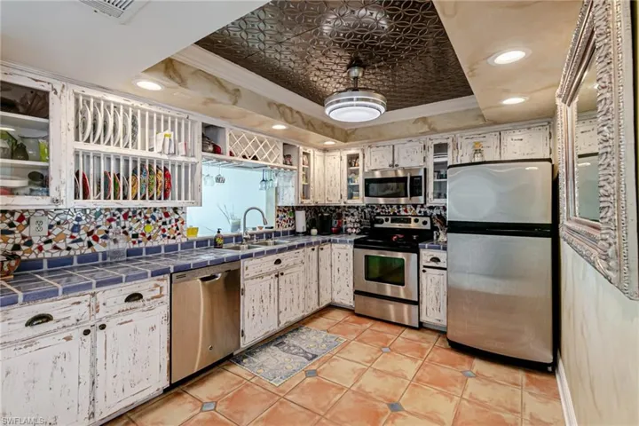 Kitchen with stainless steel appliances, crown molding, tile countertops, recessed lighting, and light tile patterned floors