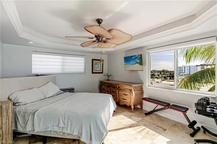 Bedroom featuring multiple windows, ceiling fan, a tray ceiling, and ornamental molding