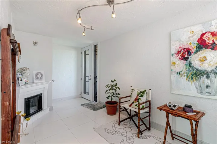 Living area featuring a textured wall, a glass covered fireplace, a textured ceiling, light tile patterned floors, and rail lighting