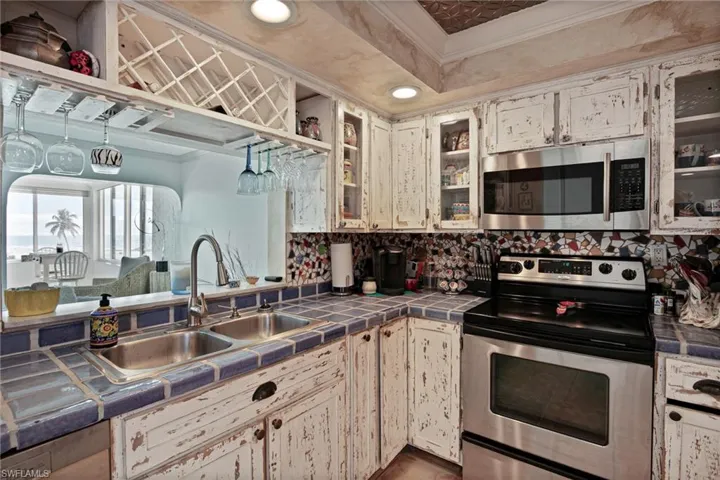 Kitchen featuring appliances with stainless steel finishes, tile countertops, glass insert cabinets, ornamental molding, and recessed lighting