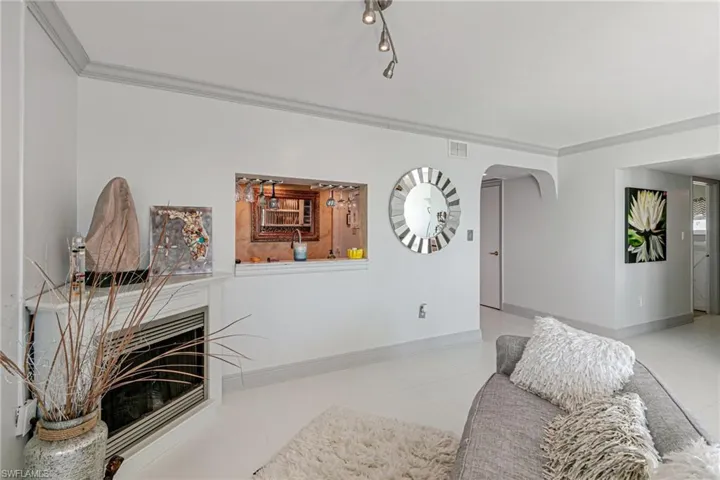 Living area featuring ornamental molding, a fireplace, arched walkways, and light tile patterned flooring