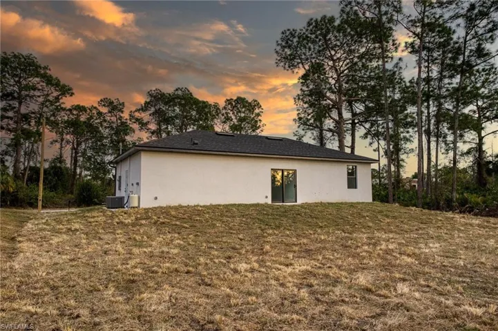 Back of property at dusk featuring a yard and stucco siding