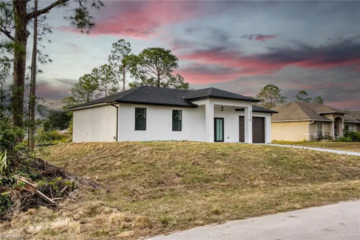 View of front of property with stucco siding, an attached garage, and a front lawn
