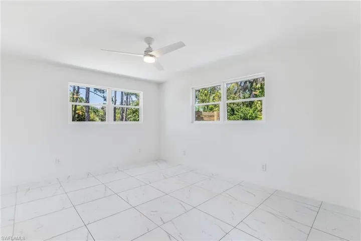 Second bedroom featuring ceiling fan and light tile floors
