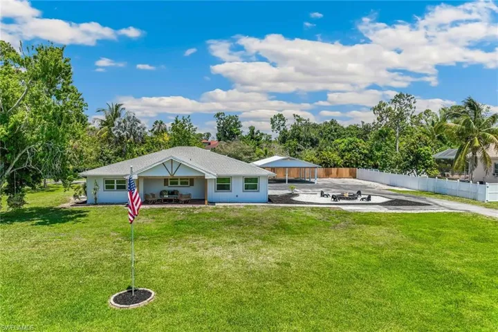 Front of house with a lanai, a yard, and a fire pit
