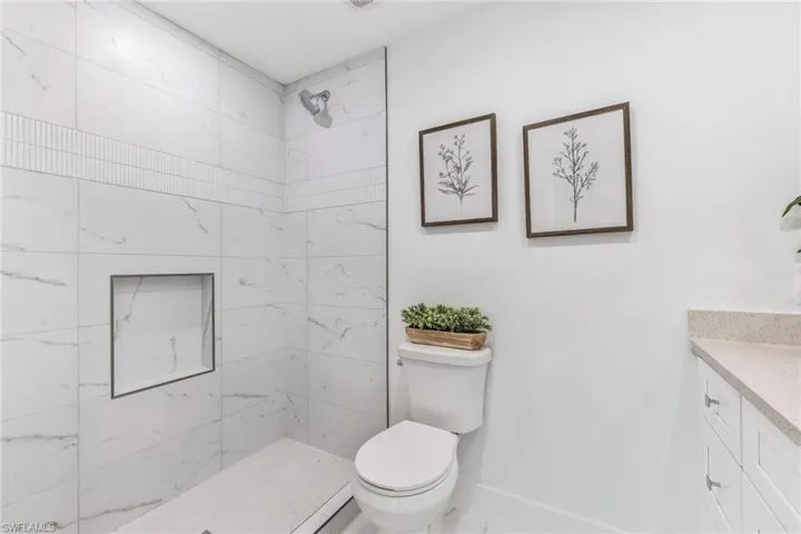 Bathroom featuring tiled shower, toilet, and vanity