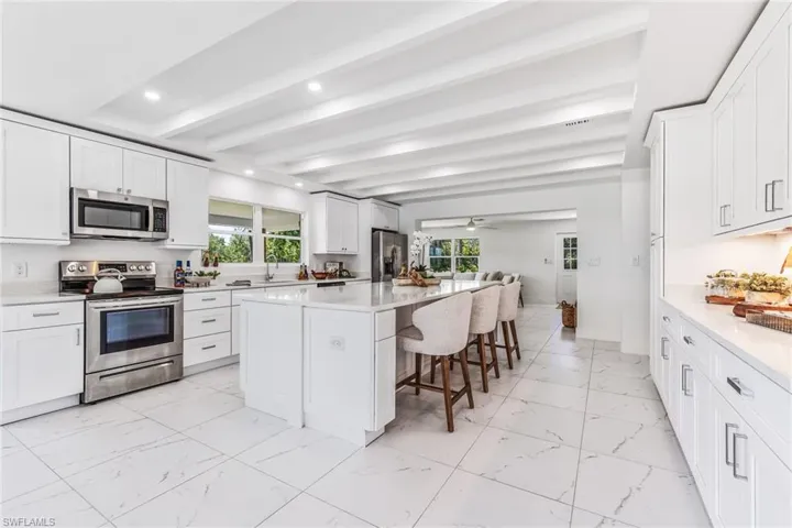 Kitchen with beamed ceiling, stainless steel appliances, a center island, and a wealth of natural light
