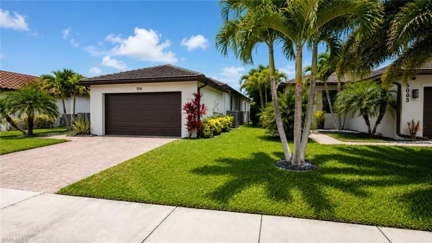 Exterior stucco facade with a dark brown garage door, a paver driveway, and a tiled roof
