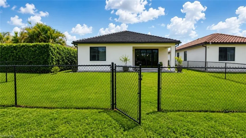 Expansive rear yard featuring a manicured lawn and black chain-link fencing
