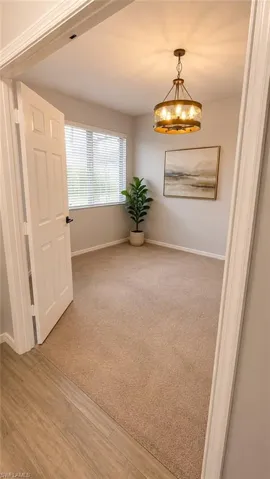 Bright room featuring a window with blinds, a prominent ceiling-mounted light fixture, and carpeted flooring
