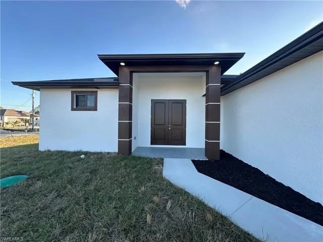 Doorway to property featuring a yard and stucco siding