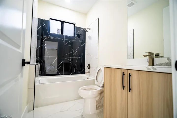 Bathroom featuring vanity, shower / bathtub combination, and marble look tiles