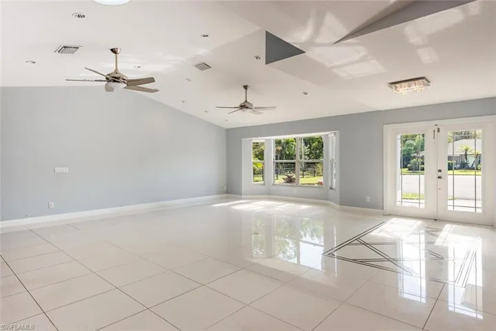 Tiled empty room with french doors, vaulted ceiling, and plenty of natural light