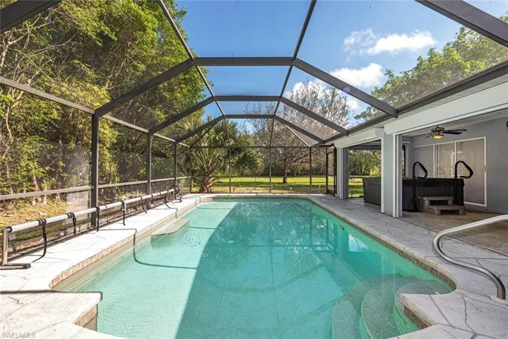 View of swimming pool with glass enclosure, ceiling fan, and a patio