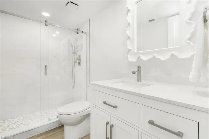 Bathroom featuring double vanity, an enclosed shower, hardwood / wood-style flooring, and toilet