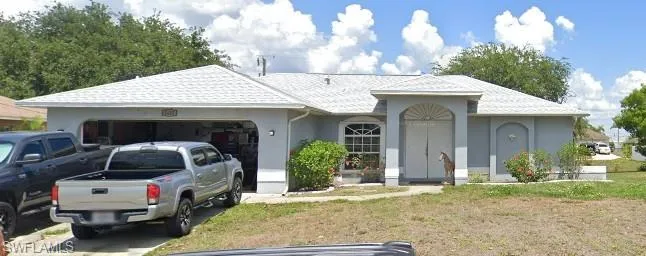 View of front of house featuring an attached garage, stucco siding, driveway, and a front yard