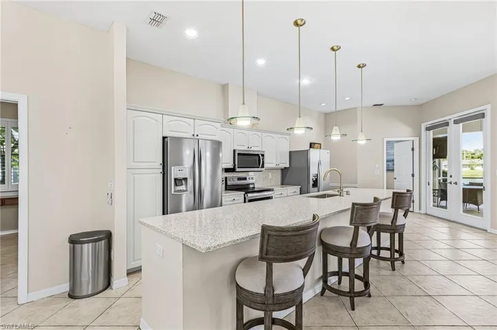 Kitchen featuring a central island with a light-toned countertop, white cabinetry, stainless steel appliances, and tile flooring
