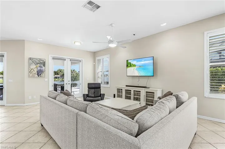 Recessed lighting, ceiling fan, neutral wall tones, plantation shutters, and large format tile flooring