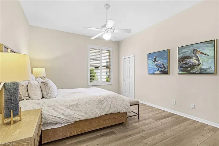 Vaulted ceiling with a ceiling fan, wood-finish flooring, plantation shutters, and a white interior door