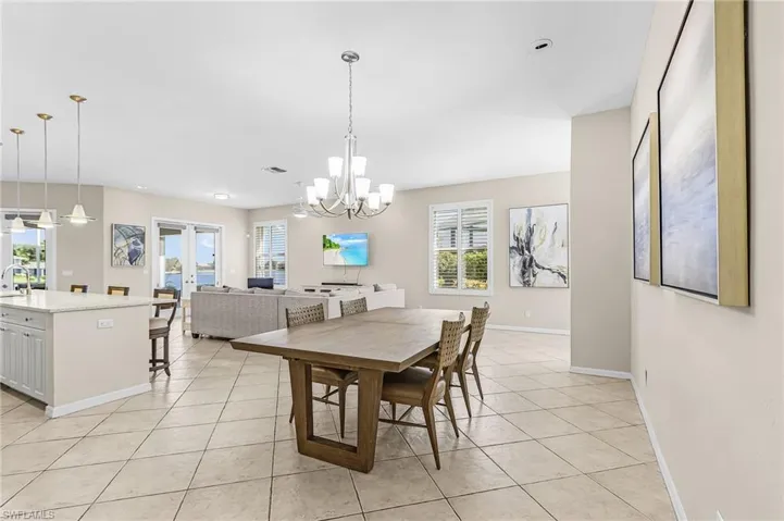 Open-concept living area featuring a kitchen island with pendant lighting, a dining area with chandelier, and tile flooring throughout