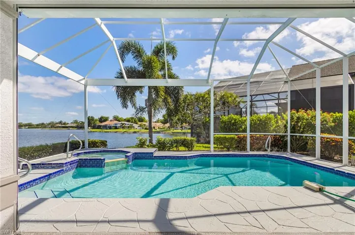 Screened lanai featuring a swimming pool, integrated spa, and patterned pool deck