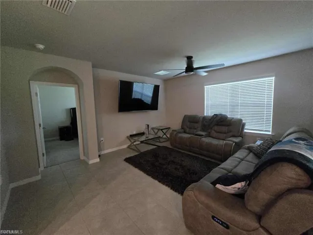 Living room featuring arched walkways and ceiling fan