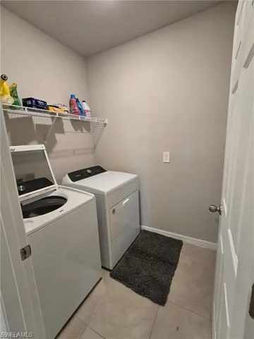 Laundry area featuring washing machine and clothes dryer and light tile patterned flooring