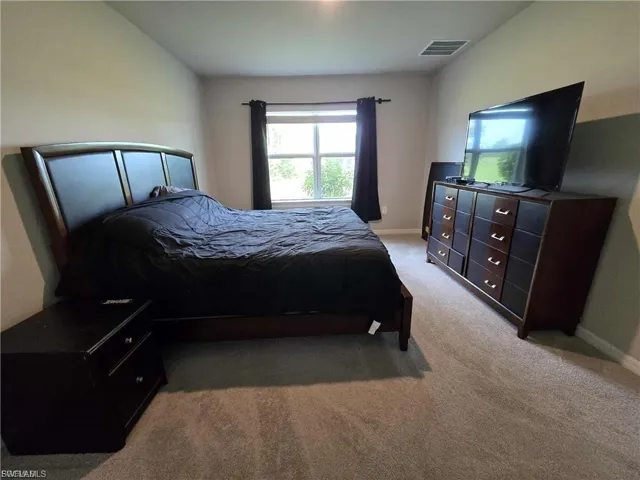 Bedroom with light colored carpet and baseboards