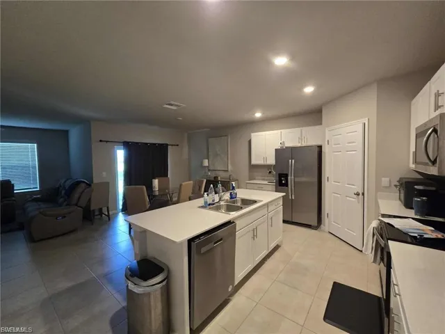Kitchen featuring open floor plan, stainless steel appliances, white cabinets, and recessed lighting
