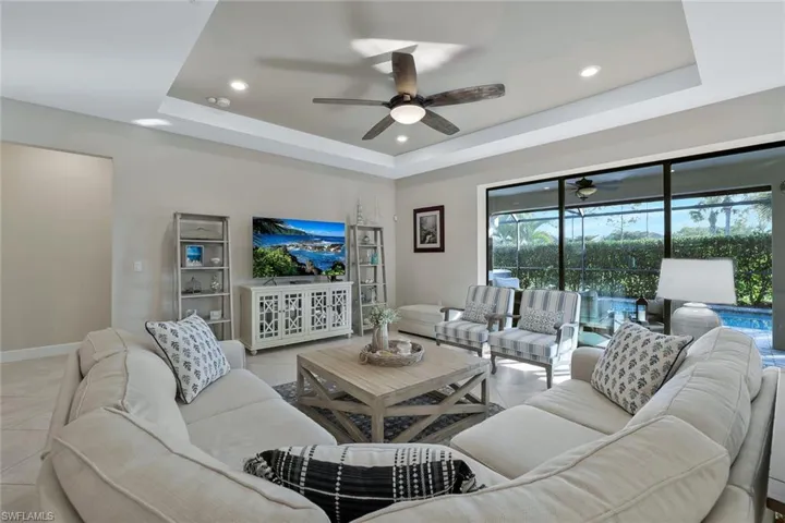 Tiled living room featuring a tray ceiling and ceiling fan