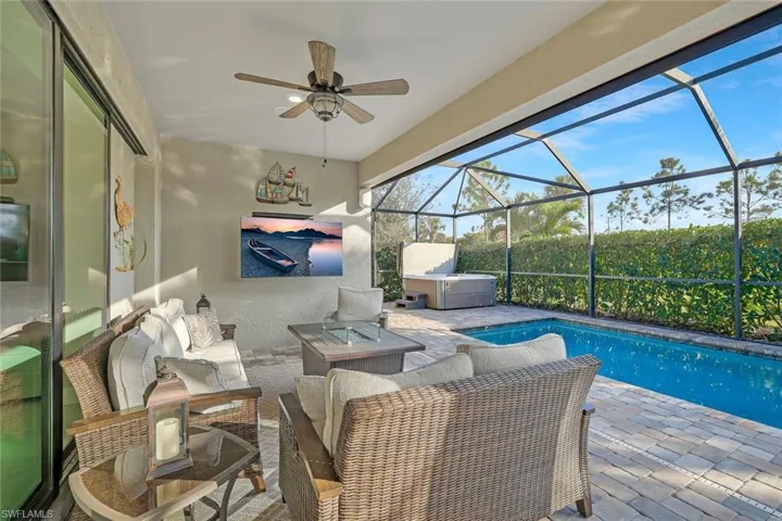 View of patio with an outdoor living space, a hot tub, ceiling fan, and glass enclosure
