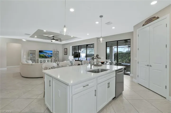 Kitchen with pendant lighting, white cabinetry, an island with sink, sink, and stainless steel dishwasher
