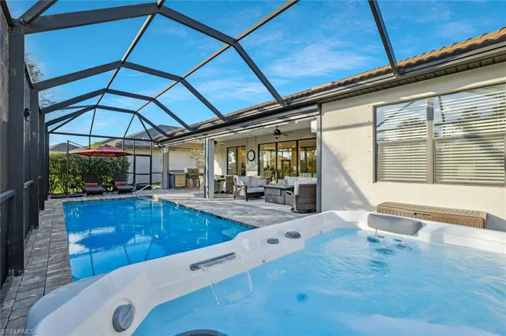 View of pool featuring a hot tub, ceiling fan, glass enclosure, an outdoor living space, and a patio area