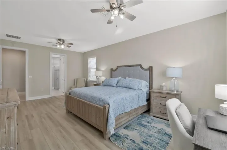 Bedroom with ceiling fan, ensuite bathroom, and light hardwood / wood-style floors