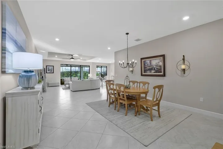 Dining room featuring light tile patterned floors, a tray ceiling, and ceiling fan with notable chandelier
