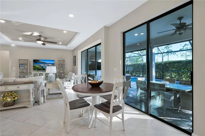 Dining area with a raised ceiling, light tile patterned flooring, and ceiling fan