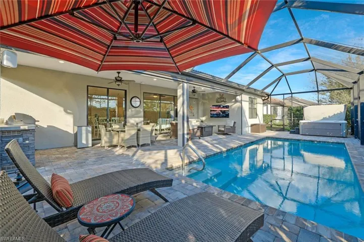 View of swimming pool featuring exterior kitchen, a patio, a lanai, and ceiling fan