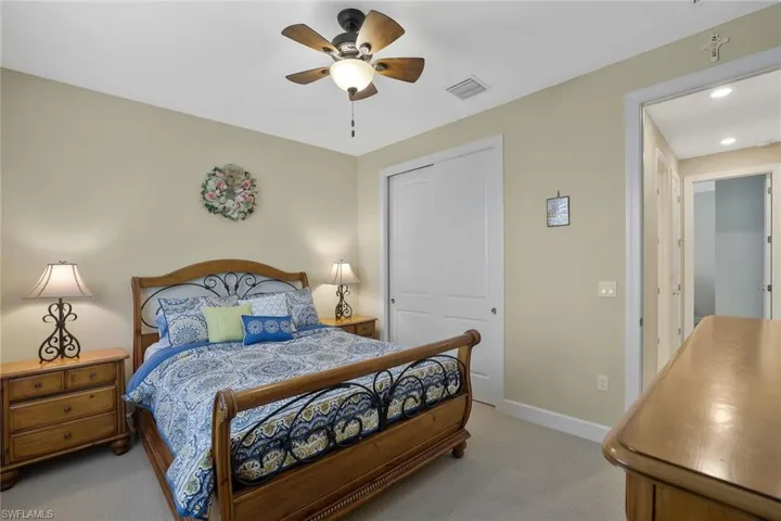 Carpeted bedroom featuring ceiling fan and a closet