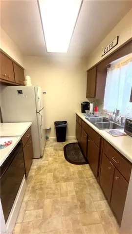 Kitchen featuring range with electric cooktop, light countertops, freestanding refrigerator, stone finish floors, and dark brown cabinetry