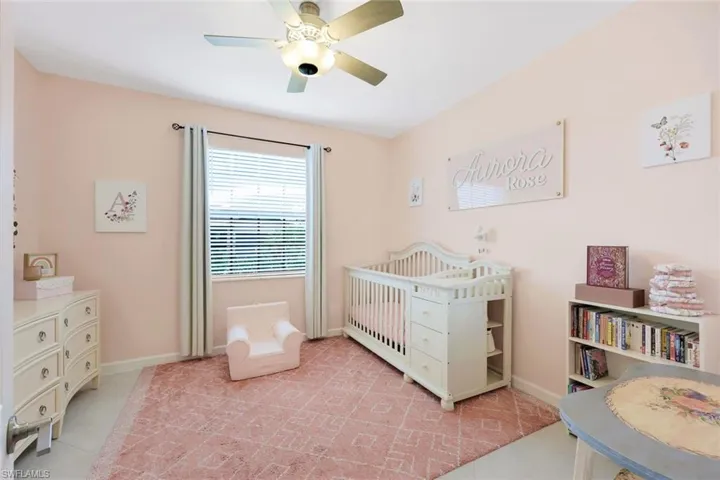 Tiled bedroom featuring ceiling fan and a crib