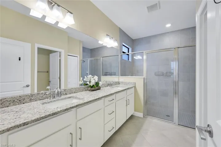 Bathroom with vanity, an enclosed shower, and tile patterned flooring