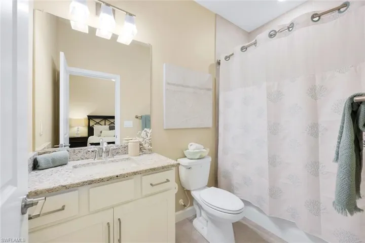 Full bathroom with tile patterned flooring, shower / bath combination with curtain, toilet, and vanity