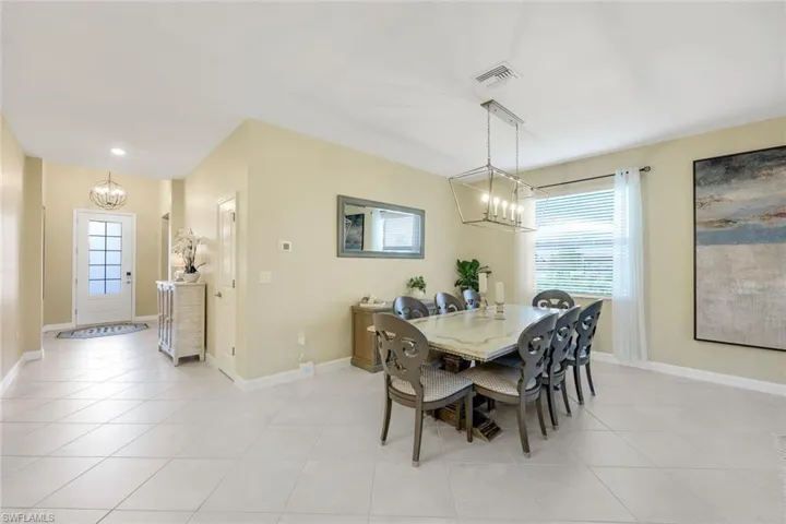 Dining room with light tile patterned floors, a wealth of natural light, and a chandelier