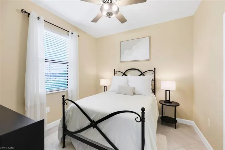 Tiled bedroom featuring ceiling fan and multiple windows