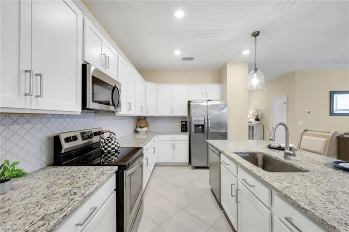Kitchen with white cabinets, backsplash, stainless steel appliances, and sink