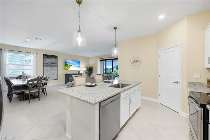 Kitchen with white cabinets, stainless steel appliances, sink, an island with sink, and pendant lighting